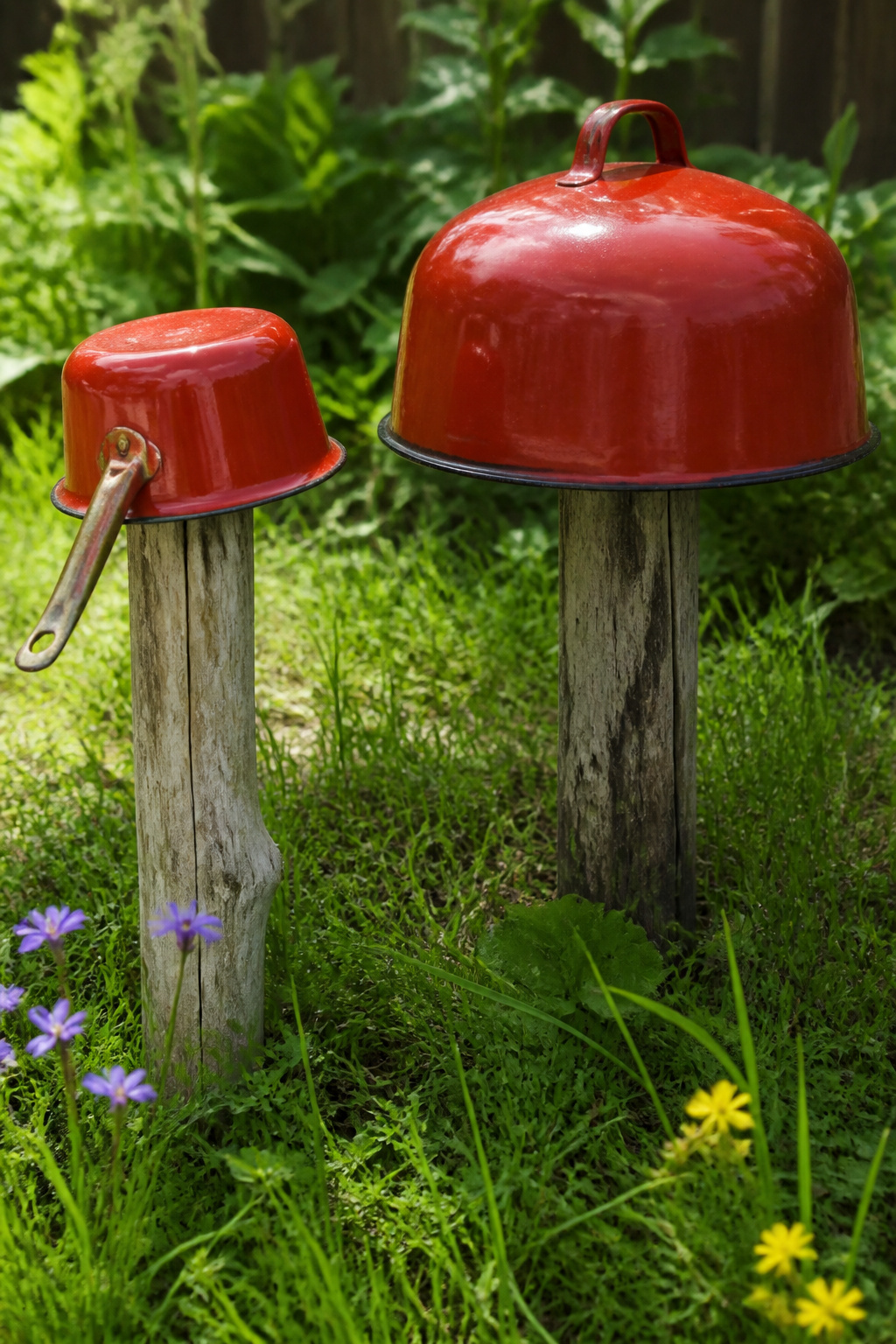 Vintage measuring cups and kitchen tins arranged as mushrooms on grass.