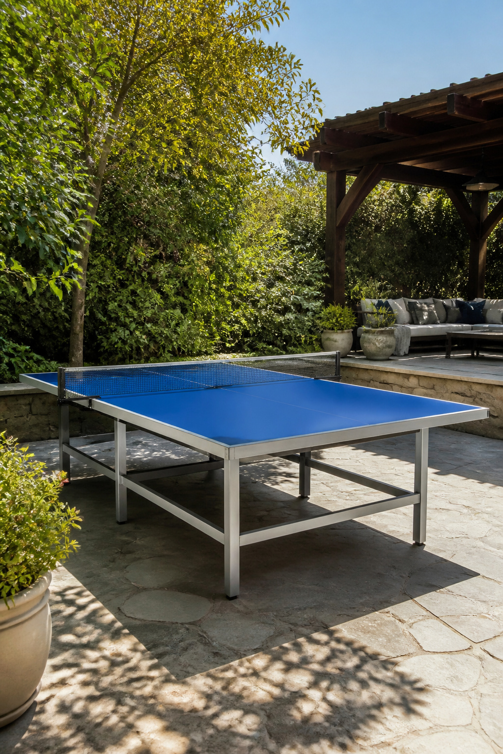 Outdoor ping pong table with a blue surface on a stone patio.