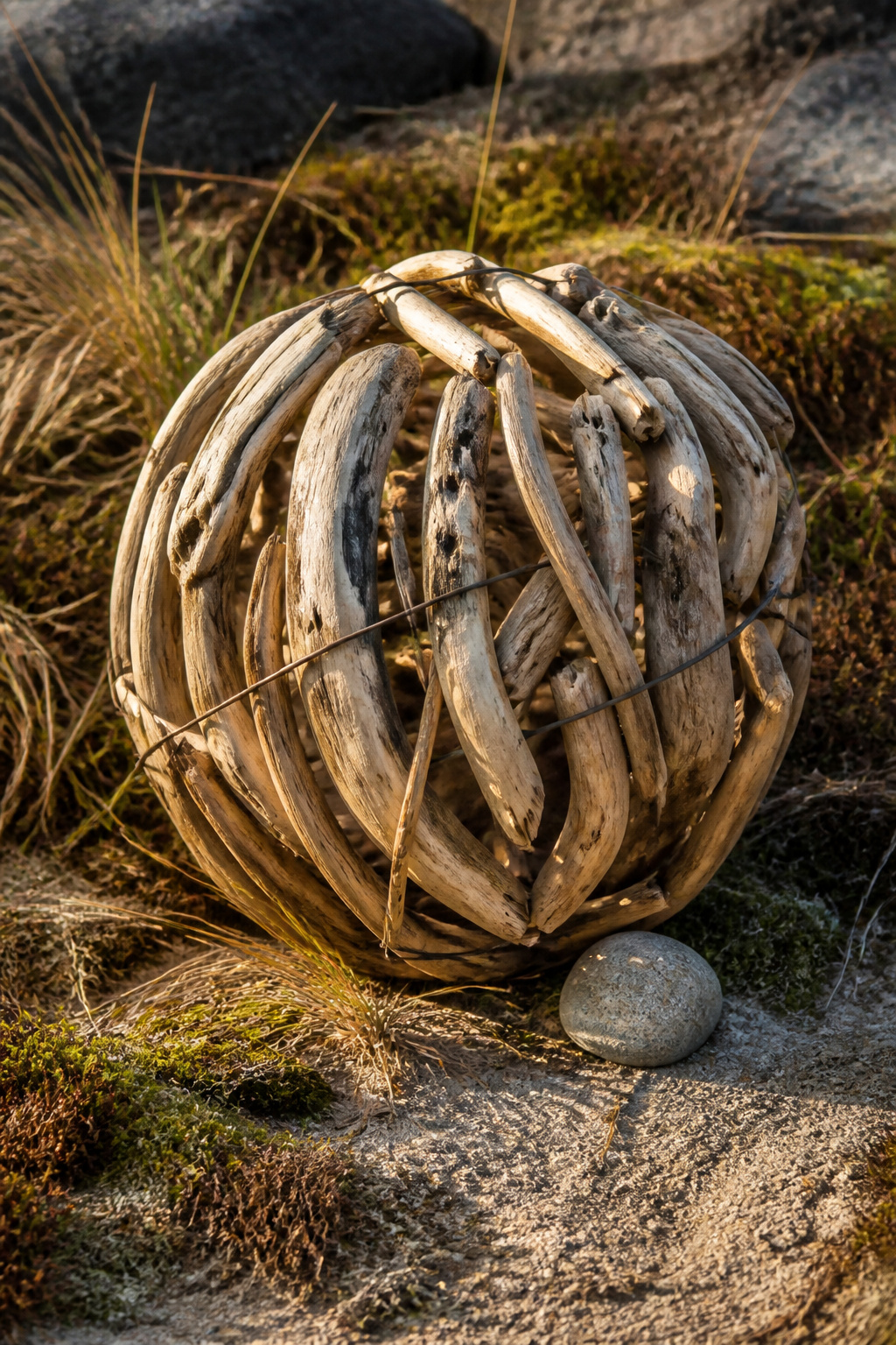 A driftwood orb made from small pieces of wood bound together.