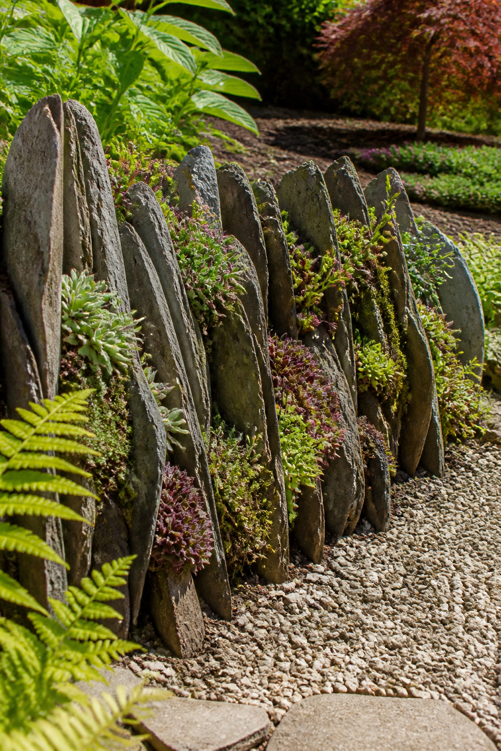 Stacked stones forming a vertical garden with plants.